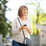 happy older woman laughing with mobile phone outside