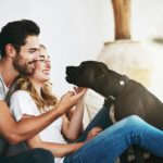 He brings joy and laughter into our lives. Shot of a couple and their pet relaxing at home.