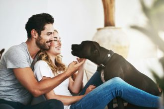 He brings joy and laughter into our lives. Shot of a couple and their pet relaxing at home.