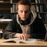 Male student reading from a book