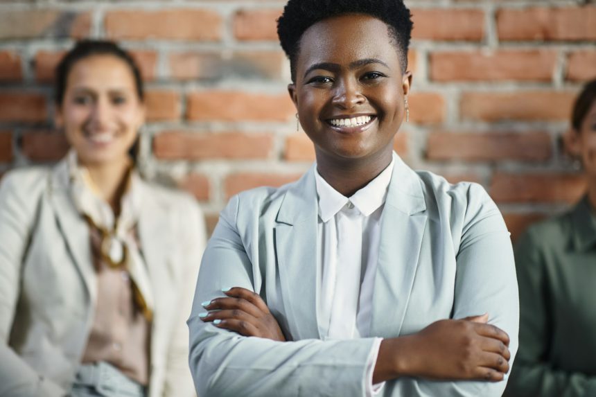 Portrait of happy black female leader and her business team at corporate office.