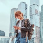 Trendy dressed redhead girl in front of skyscrapers in Moscow city