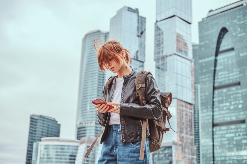 Trendy dressed redhead girl in front of skyscrapers in Moscow city