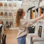 Young caucasian woman chooses furniture for her apartment in furniture store