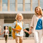Young parents escorting their kids children from school home after lessons classes